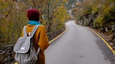 Güzel gülümseyen Asyalı kadın sonbahar yollarında yürüyor, etrafa bakıyor, doğanın güzelliğinden zevk alıyor. Yürüyüş, hobi, rahatlama, dinlenme zamanı. Ara veriyoruz..