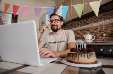 Karantina zamanında doğum gününü kutlayan bir adam. Arkadaşlarıyla sanal parti aracılığıyla doğum gününü kutlayan adam. Coronavirüs salgını 2020.