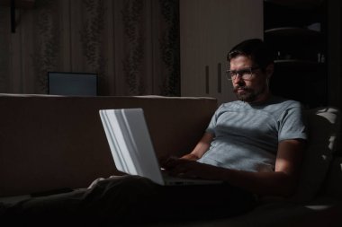 Uzaktan kumanda. Dizüstü bilgisayarda çalışan bir adam evdeki koltukta oturuyor. Metin için Boşluğu Kopyala. Serbest çalışan hipster, ortaklarıyla çalışır, çalışır ya da iletişim kurar.