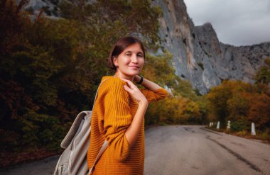 Genç ve güzel Asyalı bir hanımın dağlardaki sonbahar ormanlarında çekilmiş açık hava moda fotoğrafı. Romantik hippi kadın portresi, ılık sonbahar havası, sakin sahne. Gezgin fotoğraf serisi.