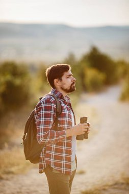 Tepedeki dürbüne bakan adam. Sırt çantalı bir adam. Vadi manzarasında yürüyüş yapan genç beyaz bir adam.