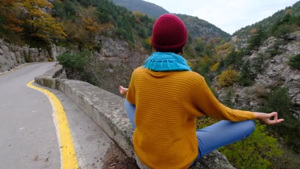 Een vrouw in een gele trui geniet van de stilte van de bergen — Stockvideo