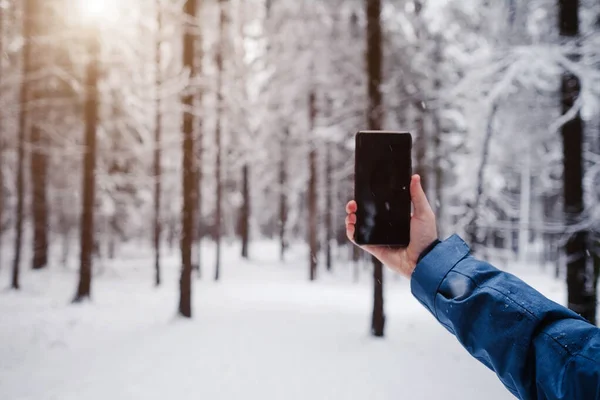 Telefon Komórkowy Ręku Człowieka Przeciwko Pięknej Zimie Pokryte Śniegiem Lasu — Zdjęcie stockowe