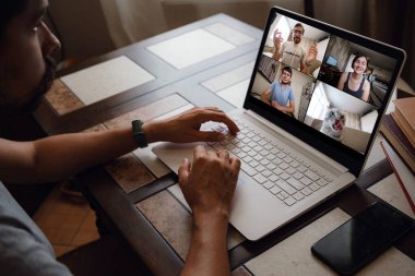 Bir adamın iş arkadaşlarıyla video konferansında planlar hakkında konuşmasına dair bir bakış açısı. Video görüşmesi için laptop kullanan çok ırklı bir iş ekibi. Evden çalışan bir grup zeki insan.