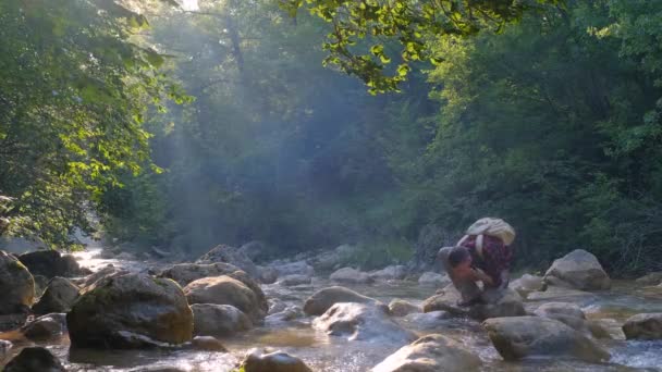 年轻人在森林里的河边岩石上放松 — 图库视频影像
