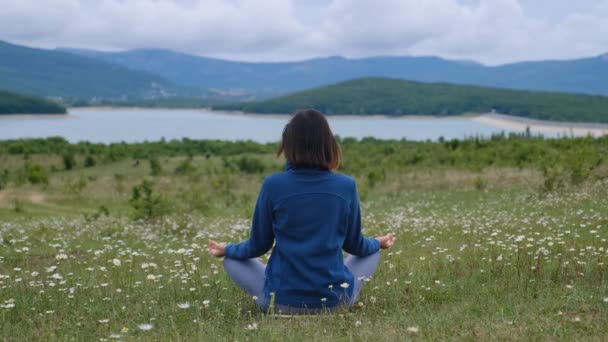 Zadní pohled na nepoznatelnou štíhlou mladou ženu sedící v lotosové poloze — Stock video