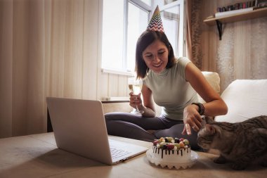 Karantina zamanında doğum gününü kutlayan bir kız. Doğum gününü arkadaşlarıyla sanal parti aracılığıyla kutlayan bir kadın. Otantik dekore edilmiş ev işyeri. Coronavirüs salgını 2020.