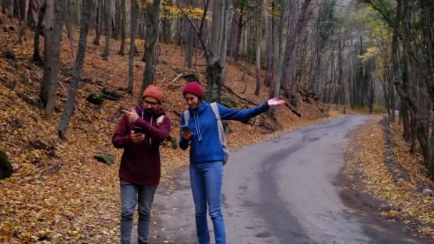 Hipster caminhantes casal com mochilas se perdeu na floresta, olhando para aplicativo de viagem smartphone — Vídeo de Stock