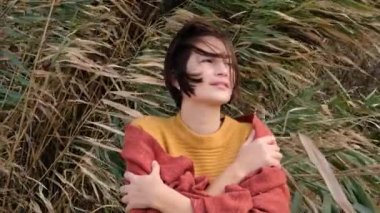 Sarı kazak giyen yürüyüşçü kadın soğuk güneşli havada yürüyor, rüzgarda dalgalanan saçlar....