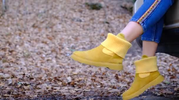 Jovem mulher balança pernas vestindo botas amarelas elegantes preso fora do automóvel moderno — Vídeo de Stock