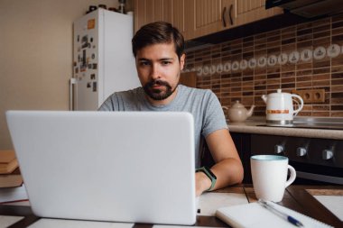 Genç adam internetten bilgisayar kullanıyor ya da çalışıyor.