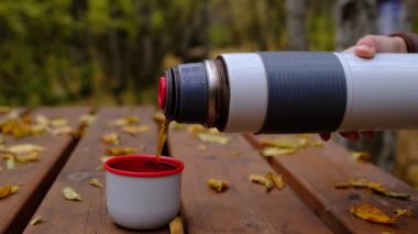Gezgin kız yürüyüş sırasında termostan çay dolduruyor..