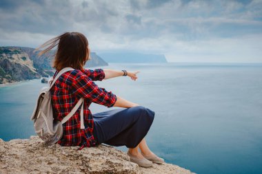 Yazın deniz kıyısında sırt çantalı bir turistle seyahat eden bir kadın. Kudretli Kayalıklar Arasında Güzel Bulutların Tadını Çıkarıyorum Okyanusla Buluşma. özgürlük fikri ve konsepti, tatil ve keşif