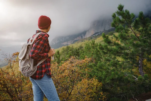 Sırt çantalı mutlu genç bir kadın sisli dağları keşfediyor. Seyahat ve seyahat tutkusu konsepti. İnanılmaz atmosferik an