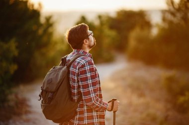 Sırt çantasıyla günbatımı dağlarında yürüyüş yapan bir adam. Seyahat yaşam tarzı seyahat macera konsepti yaz tatilleri, vahşi doğada tek başına.