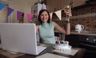 Karantina zamanında doğum gününü kutlayan bir bayan. Doğum gününü arkadaşlarıyla sanal parti aracılığıyla kutlayan bir kadın. Otantik dekore edilmiş ev işyeri. Coronavirüs salgını 2020.