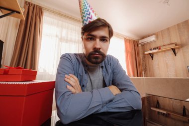 Üzgün genç adam masada oturuyor ve üzgün gözlerle bakıyor. Coronavirus salgını sırasında karantinada yalnızlık kavramı COVID-19. webcam görünümü