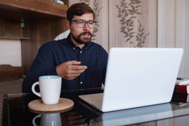 Masada oturmuş Webinar video kursunu izleyen odaklanmış bir adam online uygulama web sitesinde yeni bilgiler ediniyor. Yönetici ile konuşmak profesyonel yardım ve destek kavramı sağlar