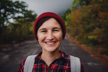 Yol ve orman arka planında mutlu Asyalı kız çantası tatil gezisi konseptinde dinlenme zamanı, klasik ton rengi ve yumuşak odak noktası