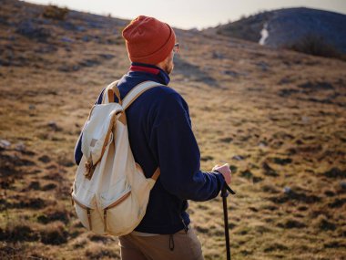 Bahar dağlarının tepesinde gün batımında duran ve doğanın tadını çıkaran genç bir adam. Dağ ve kıyı yolculuğu, özgürlük ve aktif yaşam tarzı