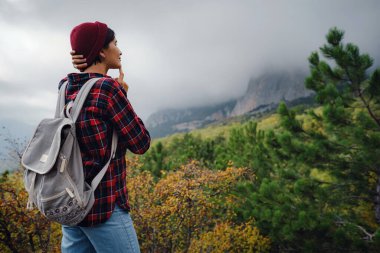 Sırt çantalı mutlu genç bir kadın sisli dağları keşfediyor. Seyahat ve seyahat tutkusu konsepti. İnanılmaz atmosferik an