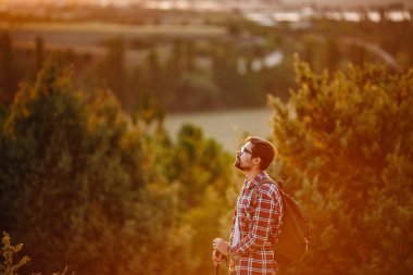 Sırt çantalı genç gezgin arka planda kayalık dağlarla dışarıda dinleniyor. Yaşam tarzı ve hobi konsepti