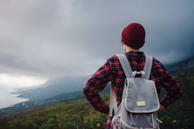 Dağların tepesinde yürüyen Asyalı şık hippi kadın. Sırt çantalı mutlu genç bir kadın sisli dağları keşfediyor. Seyahat ve seyahat tutkusu kavramı. İnanılmaz atmosferik an