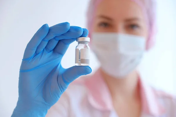 ピンクの制服を着た女医と注射器とCovid 19ワクチンを持った青い手袋 パンデミック時のコロナウイルス治療 注射および臨床試験の概念 — ストック写真