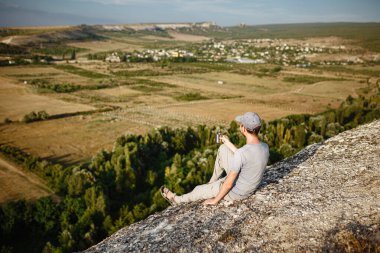 Dağlarda çay ya da kahve içen genç bir adamın dikiz görüntüsü. Yürüyüşten sonra elinde bir kupa çay tutan sakallı bir gezgin. Seyahat, yaşam tarzı, tatil.