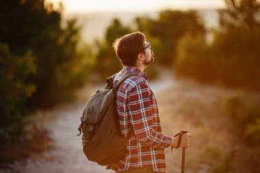 Sırt çantasıyla günbatımı dağlarında yürüyüş yapan bir adam. Seyahat yaşam tarzı seyahat macera konsepti yaz tatilleri, vahşi doğada tek başına.