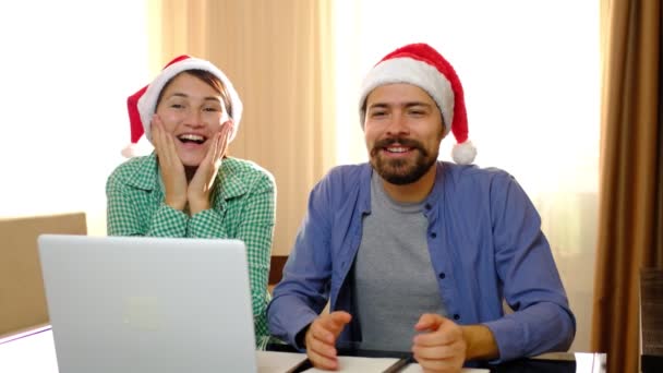 Pár jich sedí u stolu s vánočními klobouky a donese jim dárkovou krabici. — Stock video