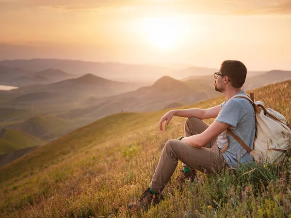 Sırt çantalı bir gezgin bir dağın tepesinde oturur ve kıyı manzarasının tadını çıkarır. Dağ ve kıyı seyahati, özgürlük ve aktif bir yaşam tarzı