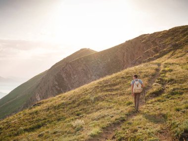 Genç adam gün batımında dağları ve deniz manzarasını izleyerek tek başına yolculuk eder. Açık havada seyahat etmenin yaşam biçimi..