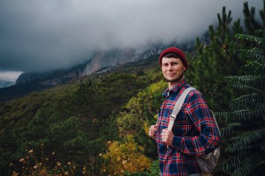 Sırt çantalı bir adam dağlarda yürüyüş yapıyor. Yaşam tarzı başarı konsepti macera, açık hava aktiviteleri, ekose gömlekli hippi kıyafetleri.