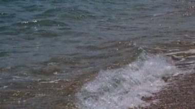 Güzel bir manzara, gün ışığında denizin kıyısında bir dalga akıyor, yakın plan..