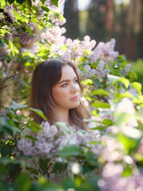 Leylak kokusunun tadını çıkaran güzel bir kadın. Şirin model, büyük beden ve çiçekler. Aromaterapi ve Bahar Konsepti
