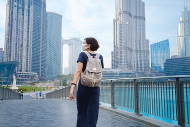 Genç ve güzel bir kadın Dubai şehir merkezinin manzarasının keyfini çıkarıyor. Birleşik Arap Emirlikleri 'nde iyi yolculuklar. Arkadan ya da arkadan bakan kadın fotoğraf makinesinden uzaklaşır.