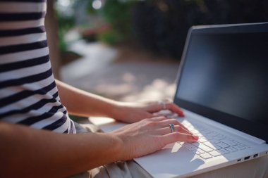 Dizüstü bilgisayarda kadın eli, parkta oturan klavyede kadın tipi. Dış ve serbest çalışma kavramı, uzaklık öğrenme