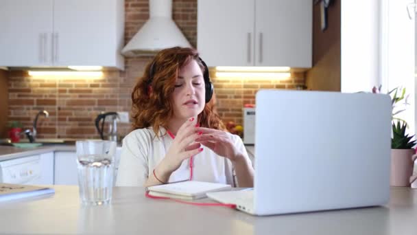 ヘッドフォンを着用する女性ノートパソコンを使用してビデオチャットで挨拶や話をします オンライングループホームオフィスからの作業チームのビデオ通話会議 Covid 19パンデミックでの自己分離 — ストック動画