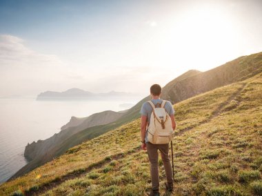 Genç adam gün batımında dağları ve deniz manzarasını izleyerek tek başına yolculuk eder. Açık havada seyahat etmenin yaşam biçimi..