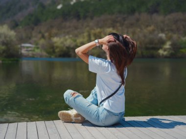 Genç bir kadın, doğal dağ gölünün güzelliğinin tadını çıkarıyor. Avrupa 'da macera seyahati. Ormanlı, ahşap köprüdeki kadın..