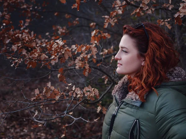 a redheaded woman walking along a mountain road in early spring. Hiker lady on nature landscape hike