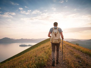 Genç adam gün batımında dağları ve deniz manzarasını izleyerek tek başına yolculuk eder. Açık havada seyahat etmenin yaşam biçimi..