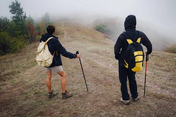 Sırt çantalı iki erkek arkadaş güz doğasında birlikte yürüyüş yapıyorlar.. — Stok fotoğraf