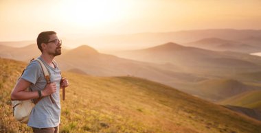 Genç adam dağların arka planında tek başına seyahat eder.