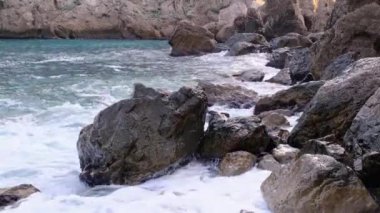 Deniz dalgaları kıyıdaki kayalara çarpıyor ve bir su patlaması yaratıyor.