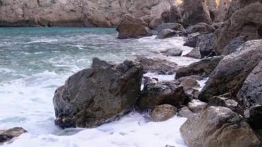 Deniz dalgaları kıyıdaki kayalara çarpıyor ve bir su patlaması yaratıyor.