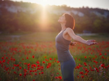 Bahar tarlasında kollarını kaldırmış güzel bir kadın.