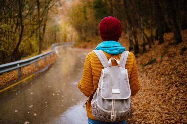 Sırt çantasıyla dağlarda yürüyen genç bir kadın.