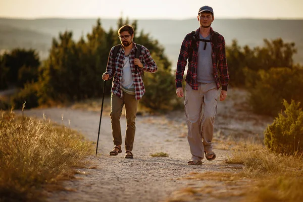 Deux hommes randonneurs profitent d'une promenade dans la nature, coucher de soleil en été — Photo
